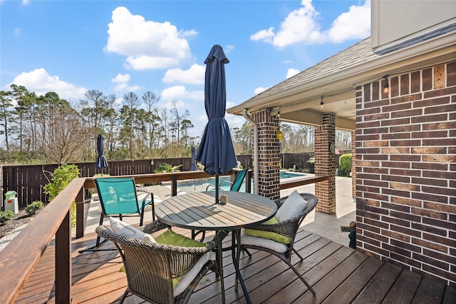 wooden terrace featuring a fenced in pool, a fenced backyard, and outdoor dining space