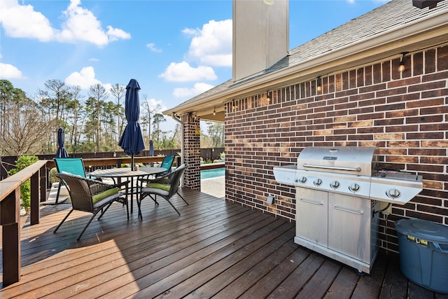 wooden deck with outdoor dining area and a grill