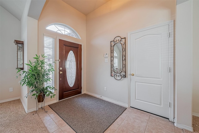 entryway with light tile patterned flooring, baseboards, and vaulted ceiling