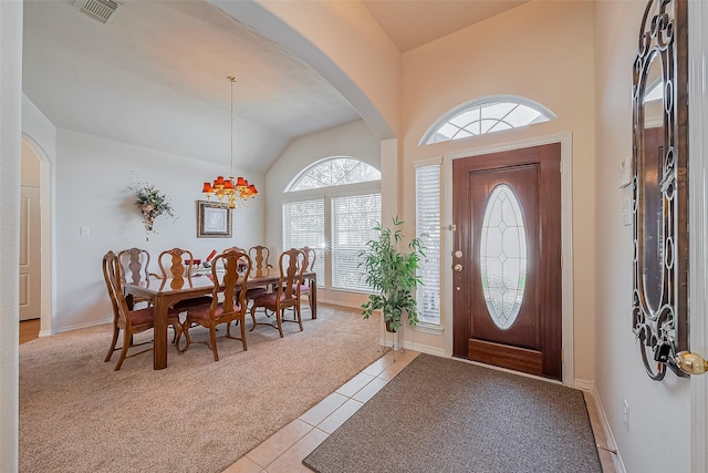 entrance foyer featuring visible vents, arched walkways, light tile patterned floors, light colored carpet, and vaulted ceiling