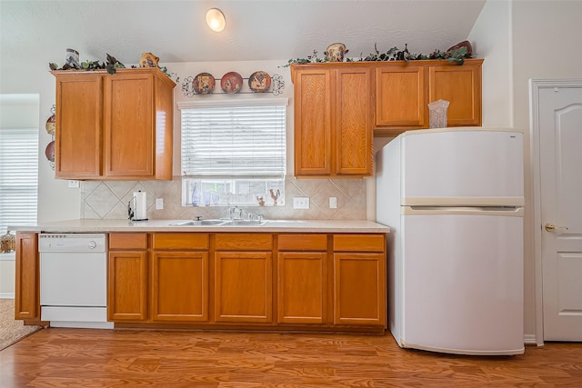 kitchen featuring white appliances, light countertops, light wood-style floors, and a sink