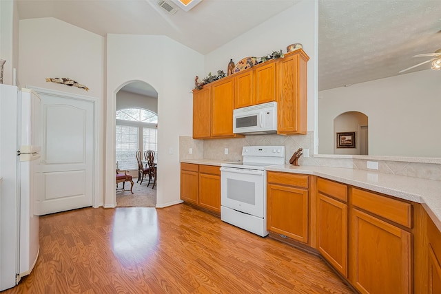 kitchen with white appliances, visible vents, arched walkways, and light countertops