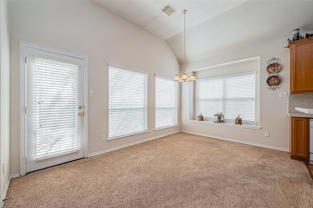 unfurnished dining area with a wealth of natural light, lofted ceiling, carpet floors, and an inviting chandelier