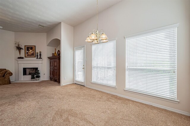 unfurnished living room featuring visible vents, carpet, a fireplace with flush hearth, arched walkways, and a notable chandelier