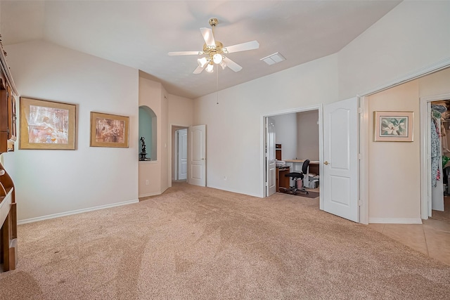 unfurnished bedroom featuring visible vents, carpet floors, arched walkways, vaulted ceiling, and a walk in closet