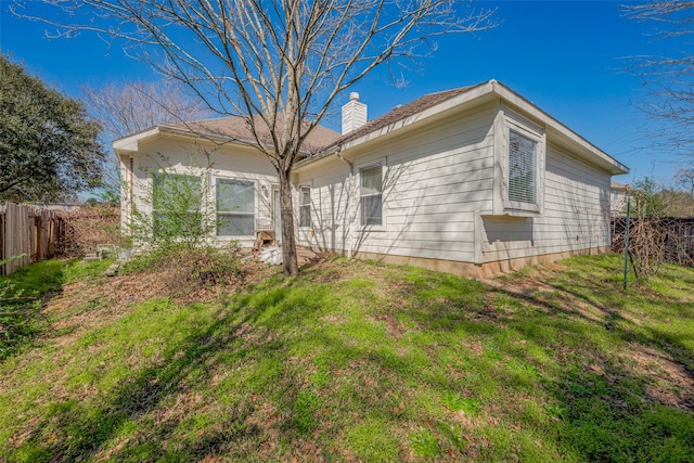 back of property with a yard, fence, and a chimney