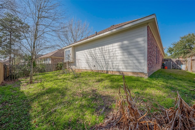 view of side of home with a fenced backyard and a yard