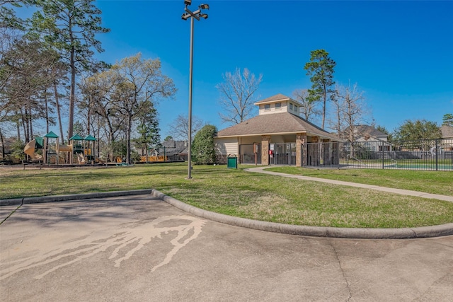 view of property's community with fence, playground community, and a lawn