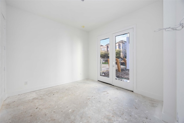 empty room with french doors, unfinished concrete flooring, and baseboards