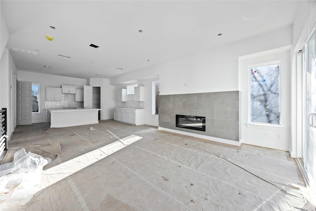 unfurnished living room featuring visible vents, plenty of natural light, and a tile fireplace