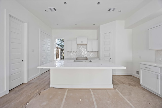 kitchen with white cabinetry, tasteful backsplash, and visible vents