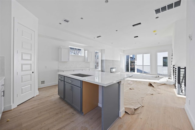 kitchen with open floor plan, visible vents, tasteful backsplash, and light wood-style floors