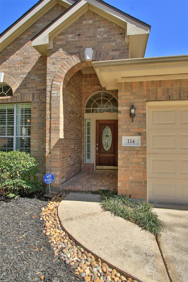 doorway to property featuring brick siding and an attached garage