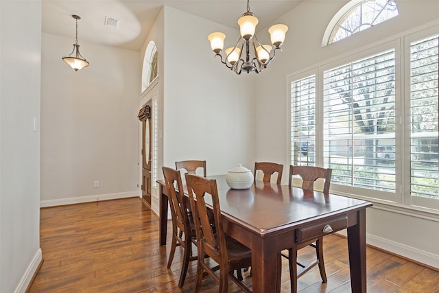 dining room featuring a notable chandelier, visible vents, baseboards, and hardwood / wood-style floors