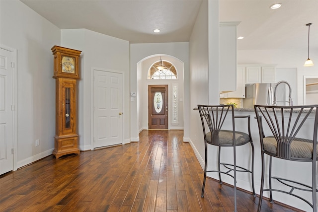 entryway with arched walkways, recessed lighting, baseboards, and dark wood-style flooring