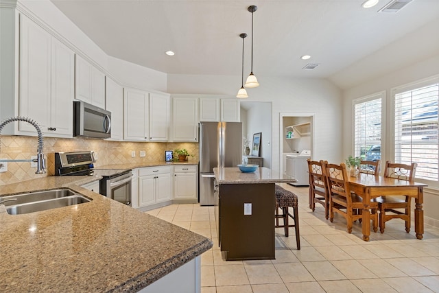 kitchen featuring visible vents, a sink, appliances with stainless steel finishes, washing machine and dryer, and backsplash