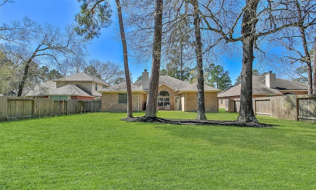 exterior space with brick siding, a chimney, a fenced backyard, and a front yard