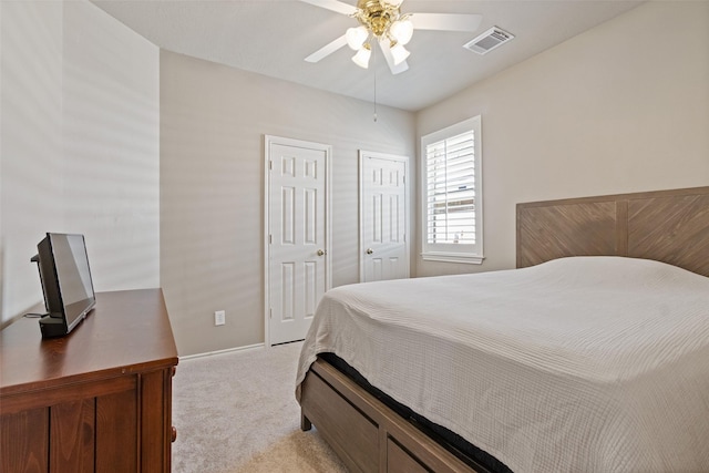 bedroom featuring visible vents, multiple closets, baseboards, light colored carpet, and ceiling fan