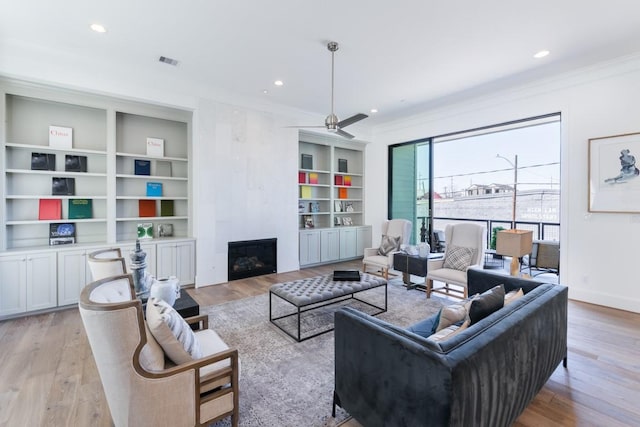 living room with recessed lighting, light wood-style flooring, a tile fireplace, and crown molding