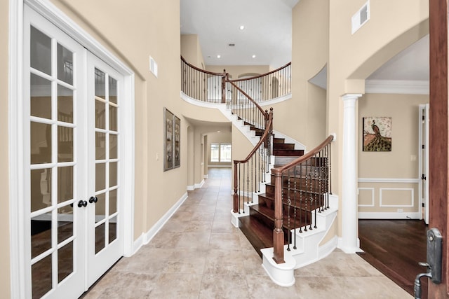 tiled foyer featuring visible vents, french doors, arched walkways, a towering ceiling, and stairs