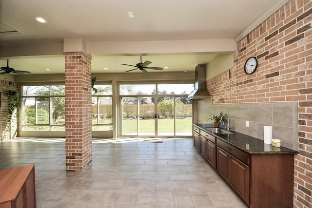 kitchen with ventilation hood, ornate columns, a ceiling fan, and a sink