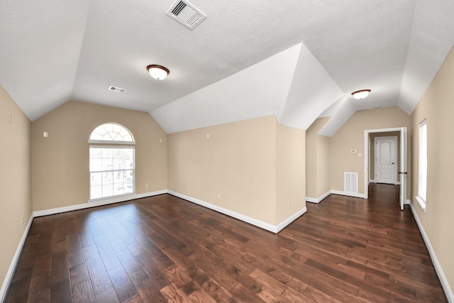 bonus room featuring dark wood finished floors, vaulted ceiling, and visible vents