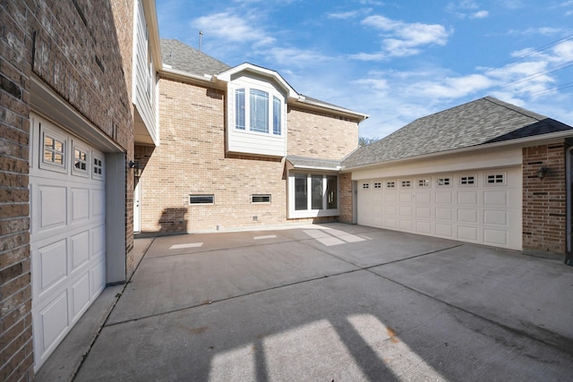 view of property exterior with a garage, brick siding, roof with shingles, and driveway