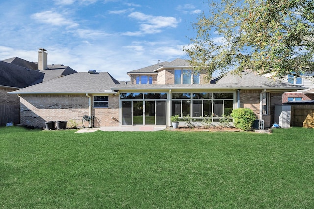 rear view of property with central AC, a lawn, brick siding, and a sunroom