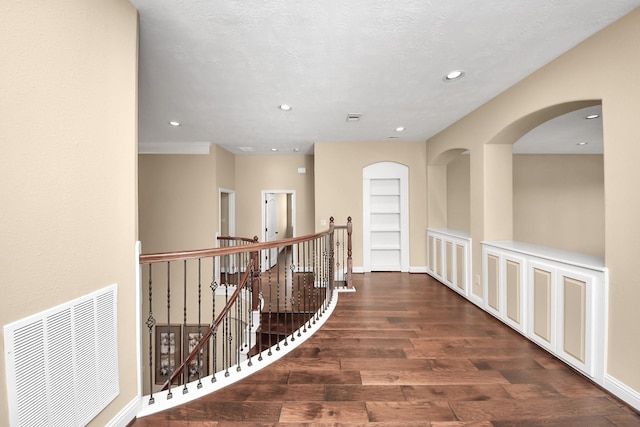 hallway with recessed lighting, visible vents, an upstairs landing, and wood finished floors