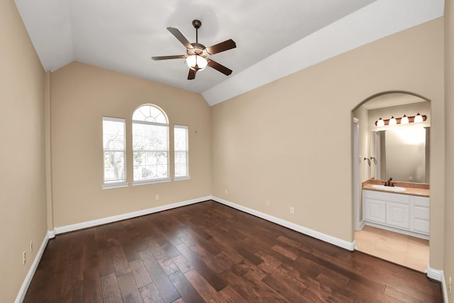 unfurnished room featuring dark wood-style floors, vaulted ceiling, a ceiling fan, and a sink