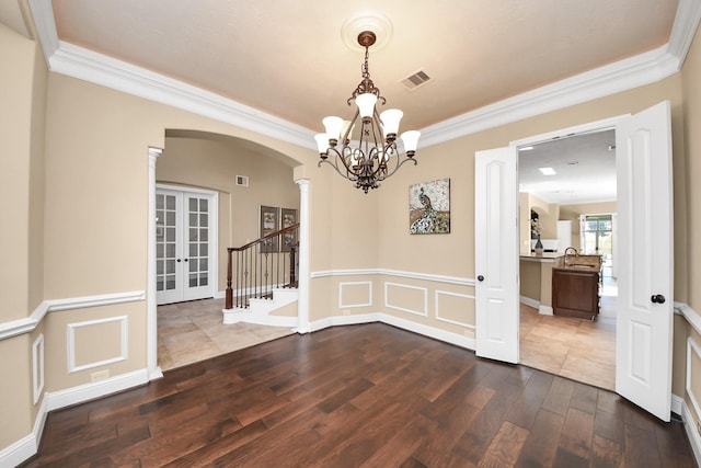 unfurnished dining area featuring visible vents, decorative columns, french doors, arched walkways, and dark wood-style flooring