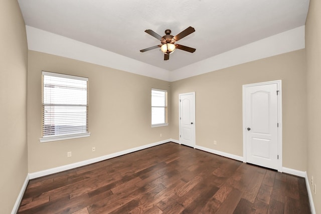 spare room with a ceiling fan, dark wood-style flooring, and baseboards