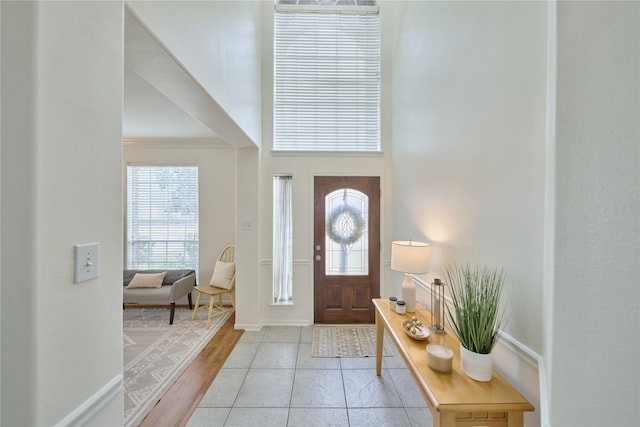 foyer with baseboards and a towering ceiling