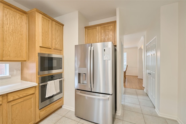 kitchen featuring stainless steel appliances, baseboards, light tile patterned flooring, and light countertops