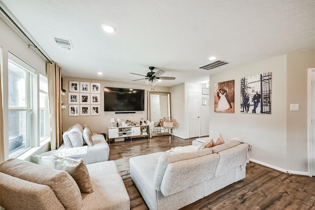 living room with dark wood-type flooring, a ceiling fan, visible vents, and baseboards