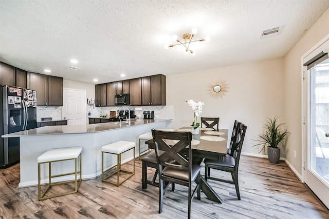 dining area featuring visible vents, baseboards, light wood-style floors, and a textured ceiling