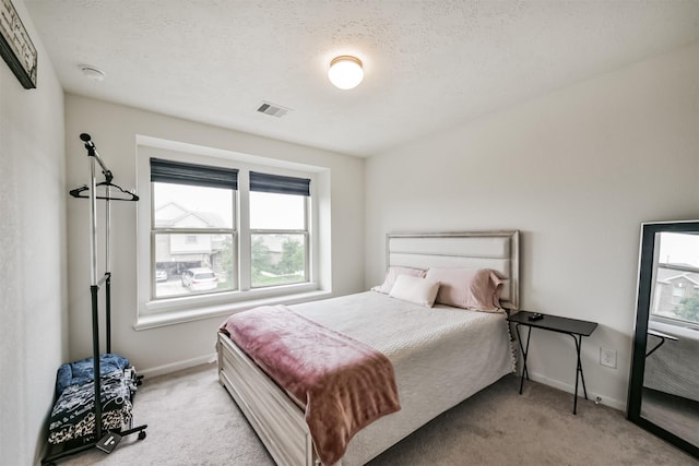 carpeted bedroom featuring visible vents, baseboards, and a textured ceiling