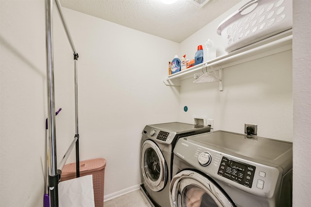 washroom with baseboards, a textured ceiling, independent washer and dryer, and laundry area