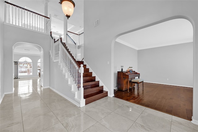 tiled entryway with stairway, arched walkways, a high ceiling, and visible vents