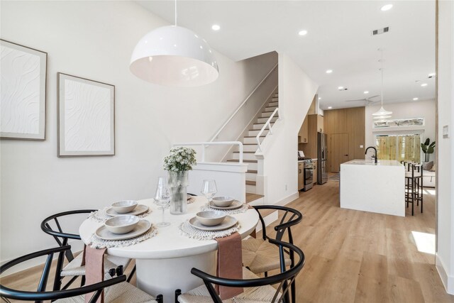 dining area featuring visible vents, light wood-style flooring, recessed lighting, baseboards, and stairs