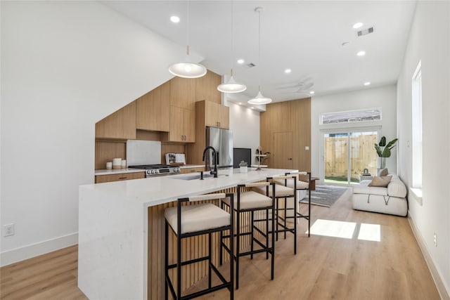 kitchen with modern cabinets, light wood-style flooring, a sink, a high ceiling, and stainless steel fridge with ice dispenser