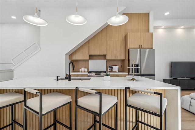 kitchen with hanging light fixtures, stainless steel refrigerator with ice dispenser, stove, modern cabinets, and a sink