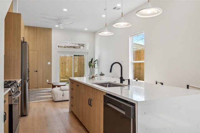 kitchen featuring visible vents, a center island with sink, a sink, stainless steel appliances, and light wood-style floors