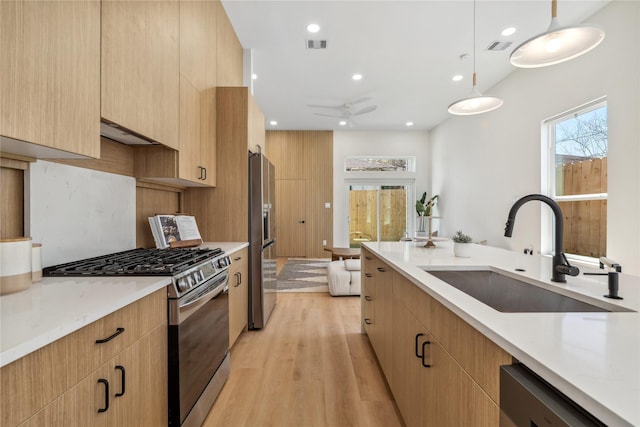 kitchen featuring visible vents, a sink, light wood-style flooring, stainless steel appliances, and modern cabinets