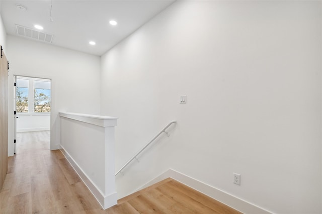 hall featuring an upstairs landing, visible vents, light wood-type flooring, and baseboards