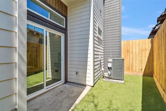 doorway to property with cooling unit, a lawn, and fence