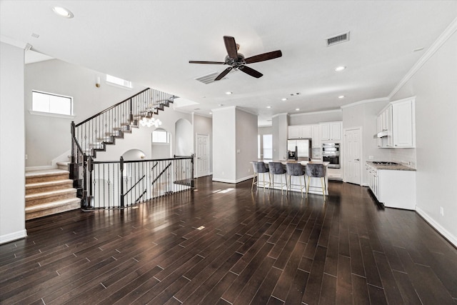 living room with dark wood finished floors, baseboards, visible vents, and a wealth of natural light