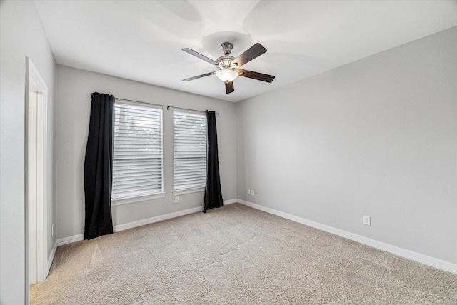 carpeted spare room with ceiling fan and baseboards