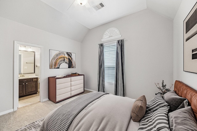 bedroom with visible vents, baseboards, light colored carpet, vaulted ceiling, and ensuite bathroom