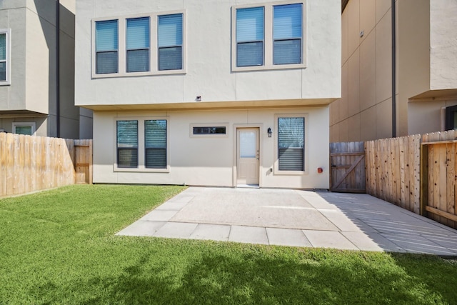 rear view of house with stucco siding, a lawn, a patio area, and fence